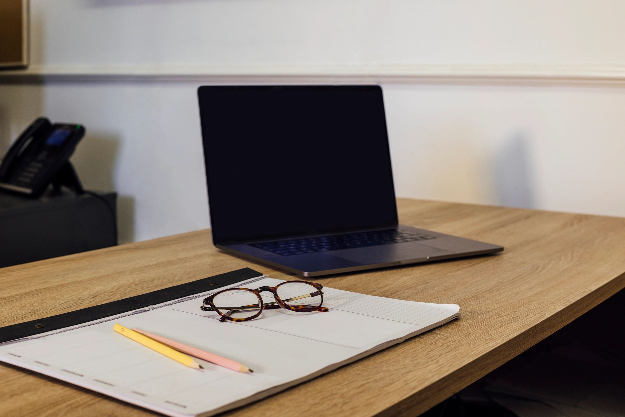 Writer's desk with laptop, planner, and glasses